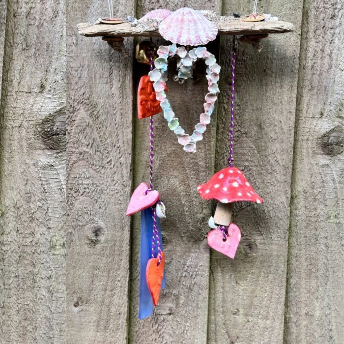 Tranquil melodies-Hand-decorated driftwood windchime mobile with tiny stones, seashells, gold bells, and hearts hanging from durable nylon for indoor or outdoor display.