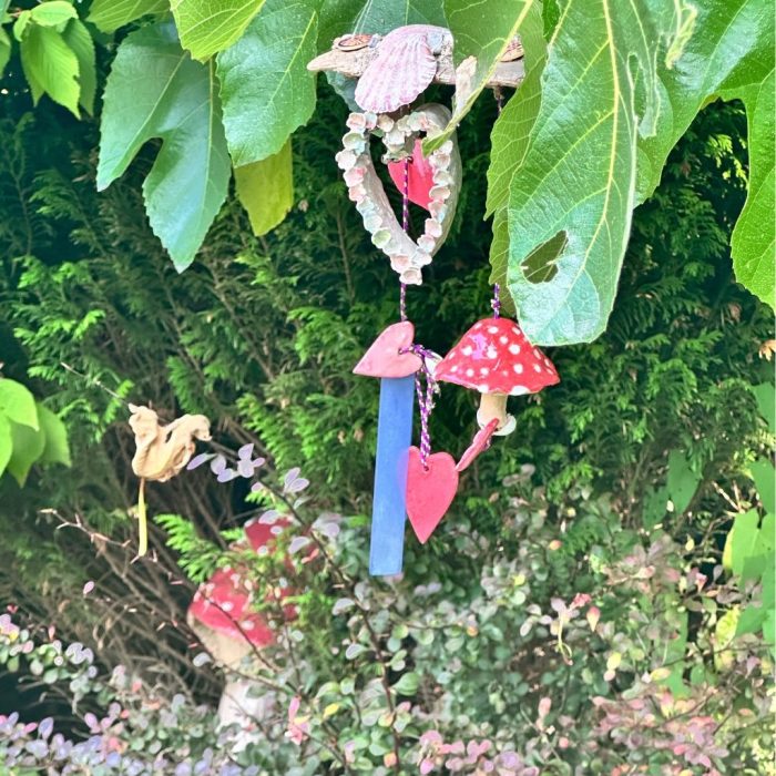 Tranquil melodies-Artistic driftwood creation with seashells, pastel flowers, and a large white heart with bells and chimes for hanging décor.