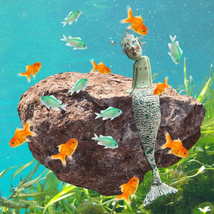 Handmade ceramic merman with green body and wire hair.