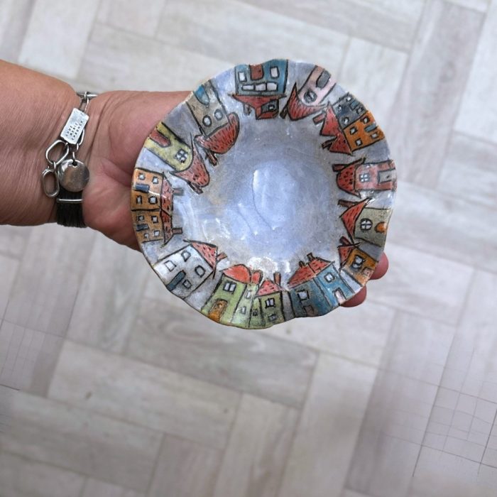 This unique dish has wavy edges and a vibrant village scene, hand-painted with character-filled houses against a calming blue backdrop.