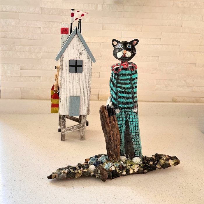 Playful handcrafted cat sculpture with bold black and turquoise stripes.
