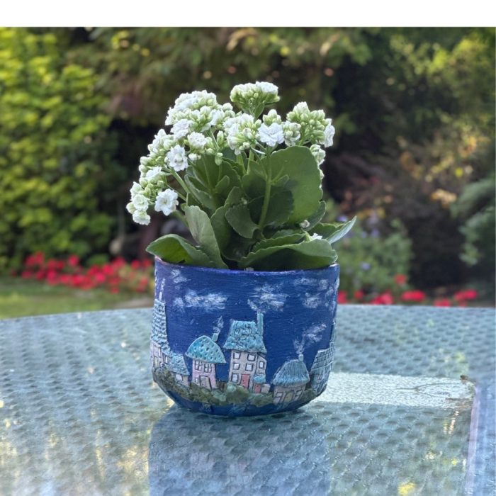 Artistic plant pot showcasing a whimsical village scene.