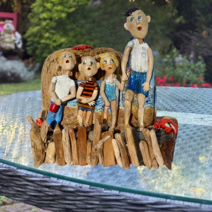Handcrafted sculpture with driftwood bodies and ceramic heads, bringing beachside humour to life.