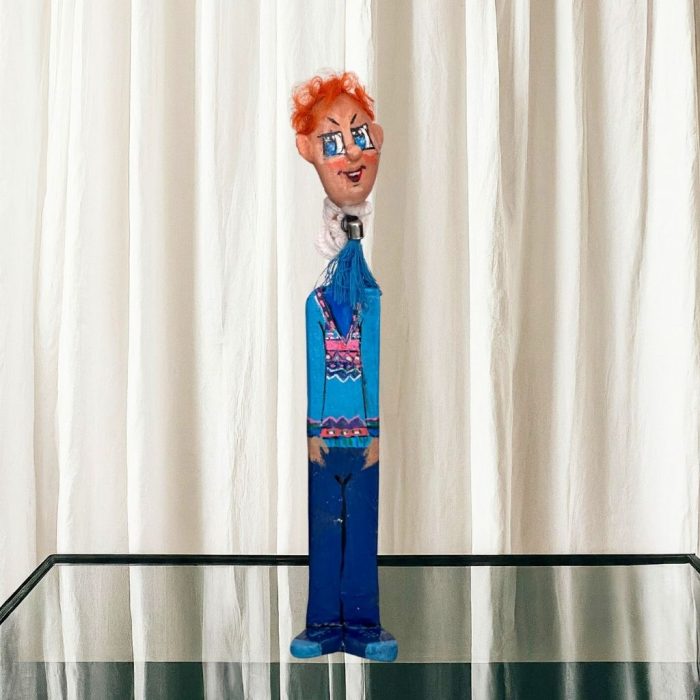 Resin-coated ceramic face with vibrant hair accents atop a sturdy ceramic stand.