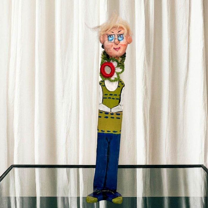 A whimsical ceramic flower figure with a colourful hand-painted stone face mounted on a ceramic body.
