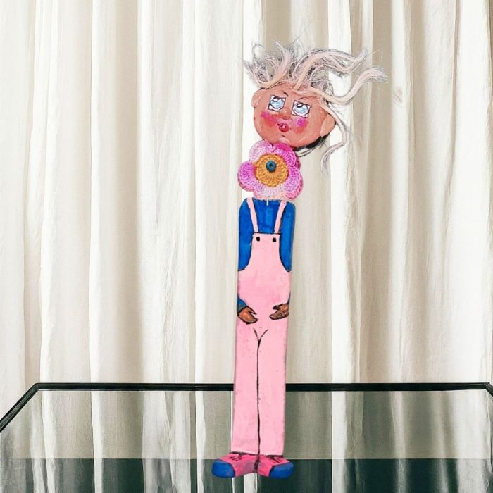 A whimsical ceramic flower figure with a colourful hand-painted stone face mounted on a ceramic body.