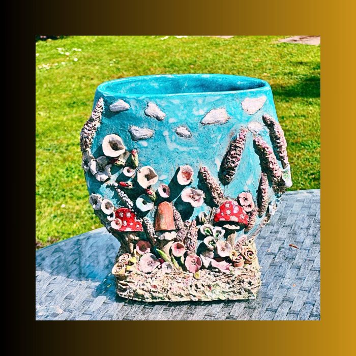 Handmade 3D ceramic vase with colourful houses on a pale blue background"